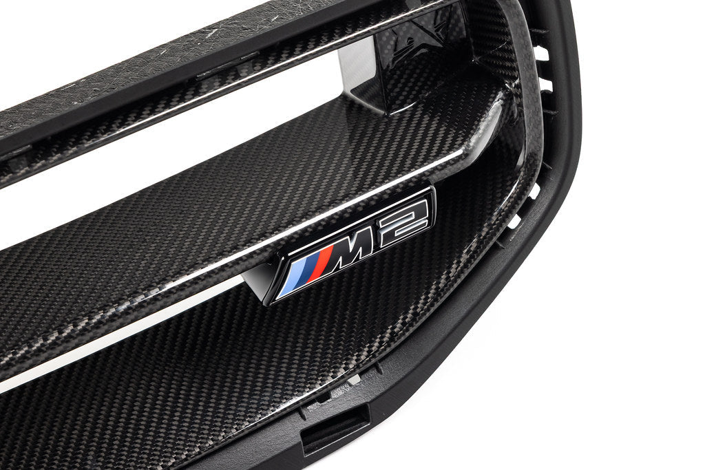 Alpha N G87 M2 LCI front grille emblem retainer with BMW OEM M2 badge installed on car exterior.