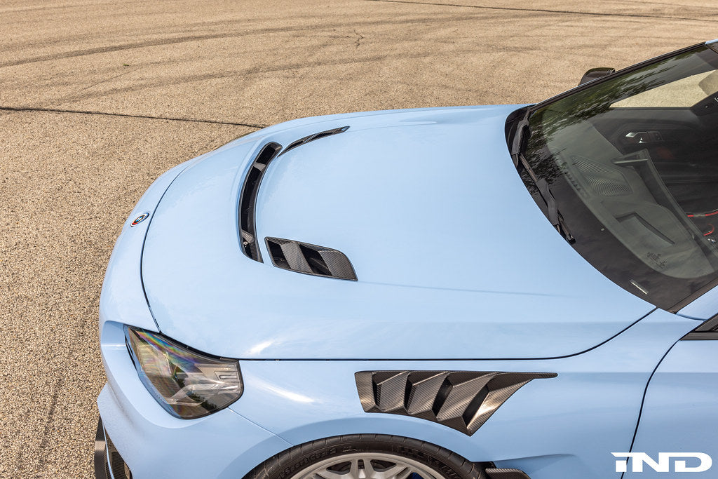 Alpha-N G87 M2 Clubsport carbon vented hood installed on a car, showcasing lightweight, aerodynamic exterior upgrade.